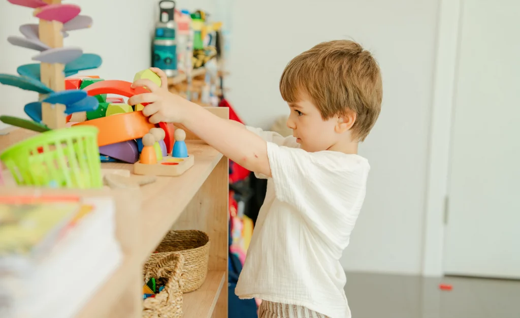 Child playing with toys on a shelf, possibly at an association.