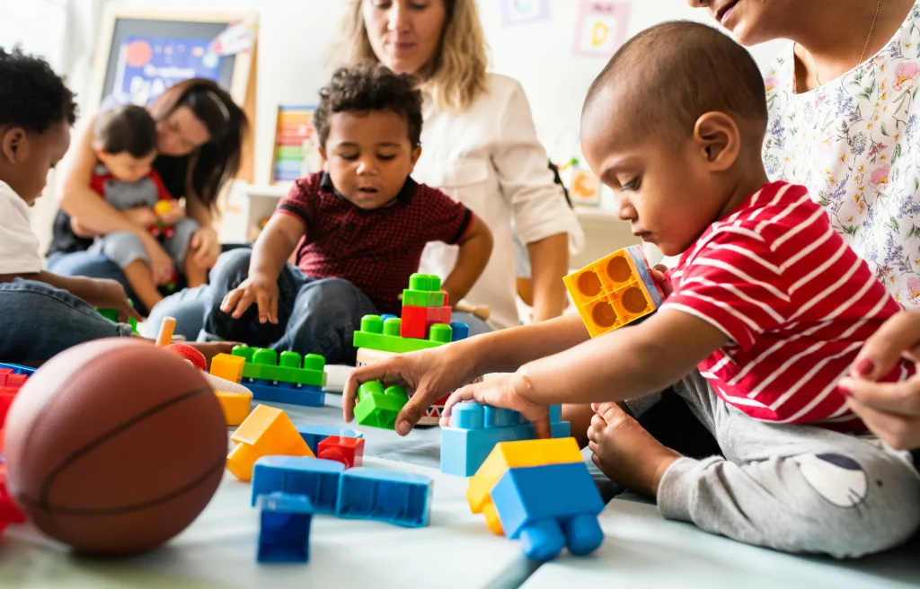 Children playing with blocks in a classroom setting, representing contact.