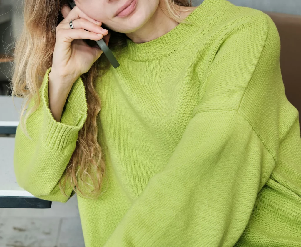 Woman in green sweater on phone. Service d'AED context.