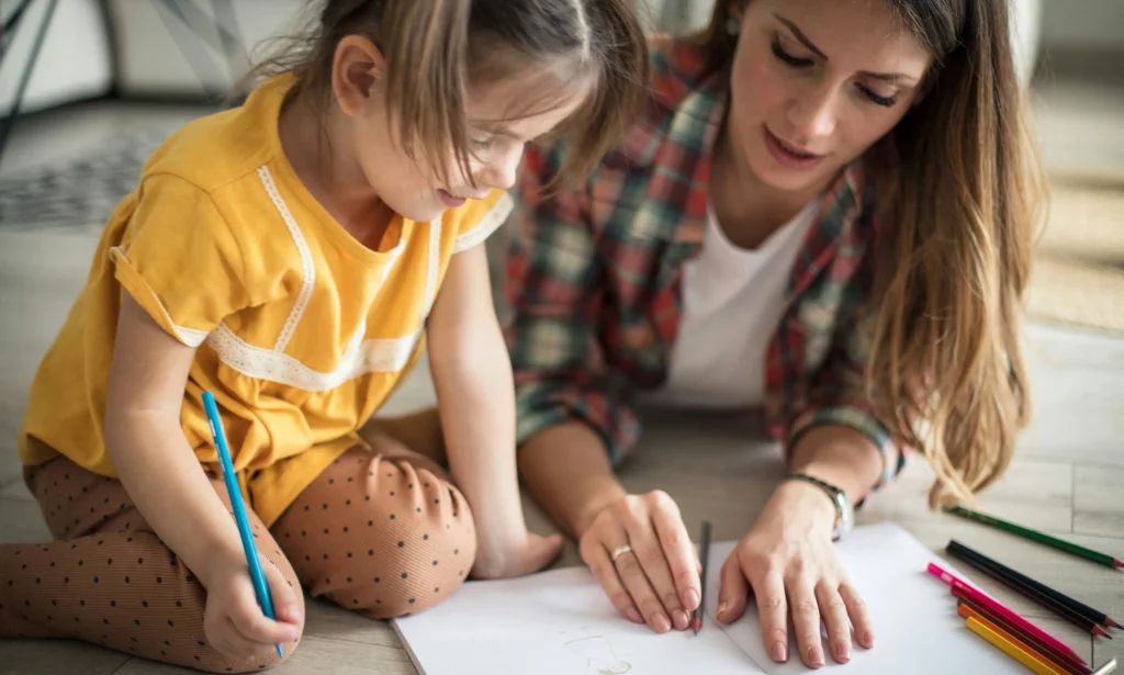 Mother and child drawing together on the floor, possibly discussing AED service options.