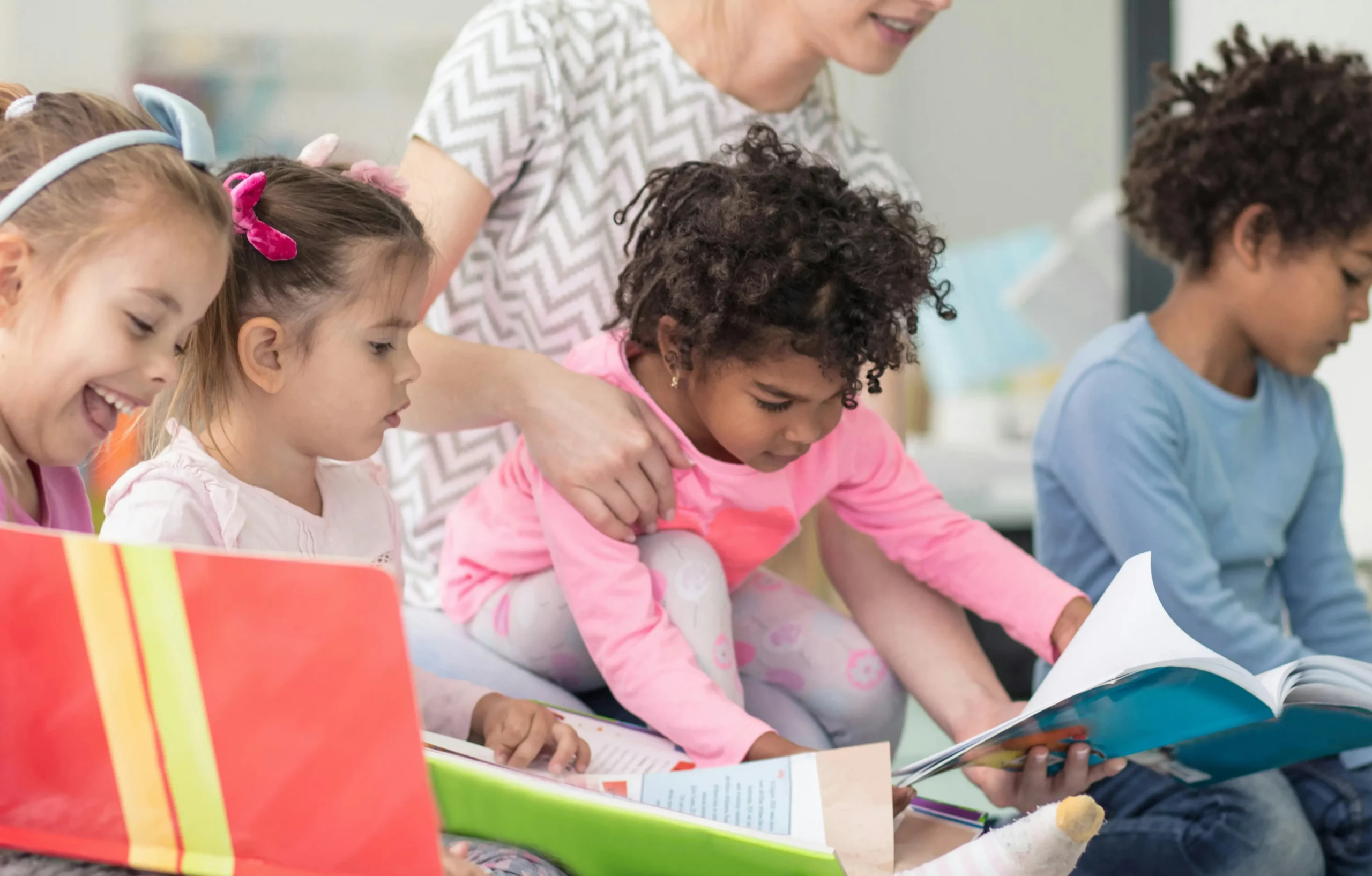 Children at a crèche in Paris 18 reading books with a teacher. Collective learning.
