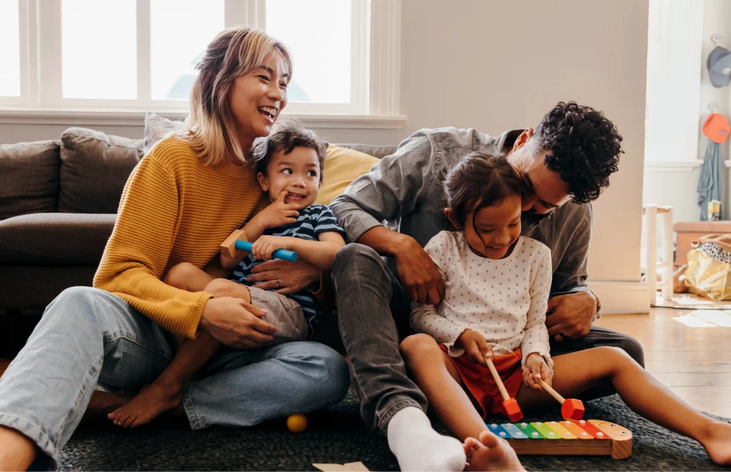 Family playing with musical toys on floor. "Notre Association" could support families like this.