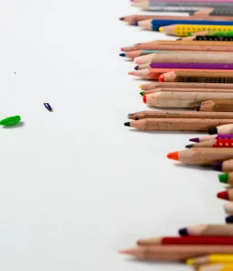 Colored pencils border on white background, with pencil shavings. Art supplies for drawing.